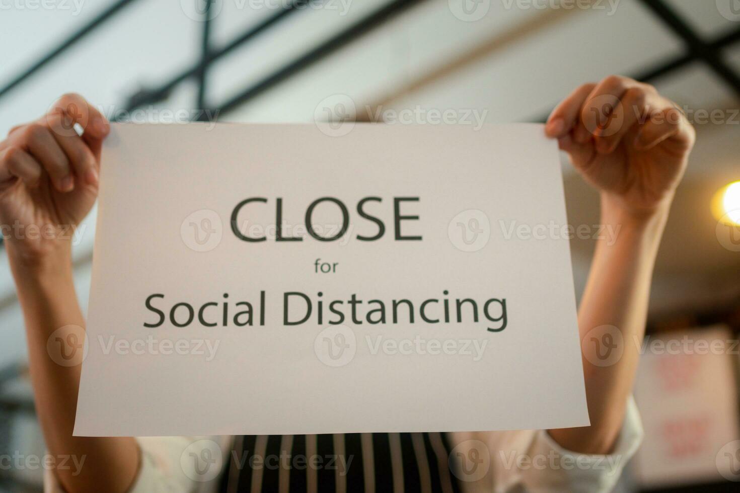 servitris innehav en tecken stänga social avstånds i en coffee foto