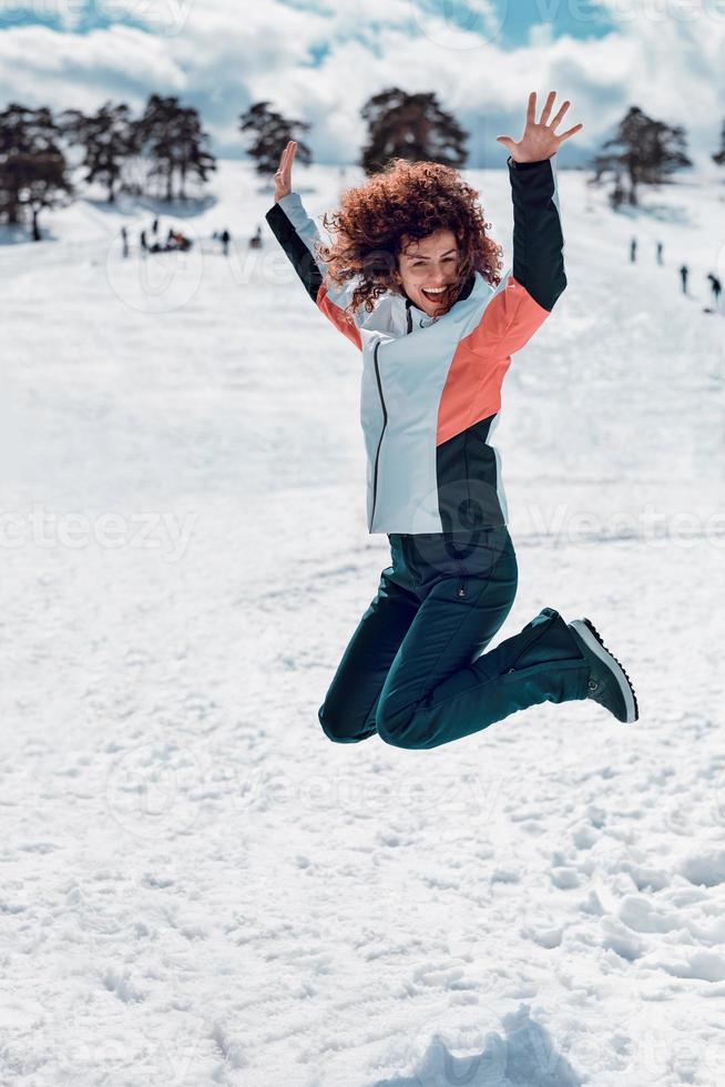 glada kvinnor som hoppar i luften och har kul på snön på den soliga vinterdagen. foto
