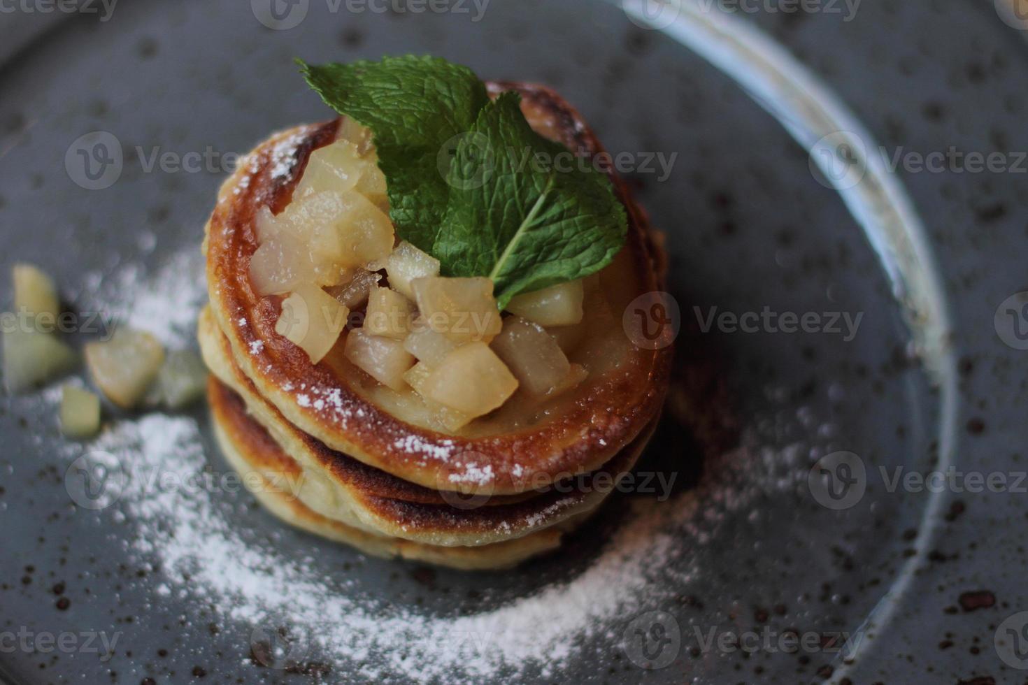 läckra nybakade pannkakor för hälsosam frukost med mynta och äpple sylt på grå tallrik foto