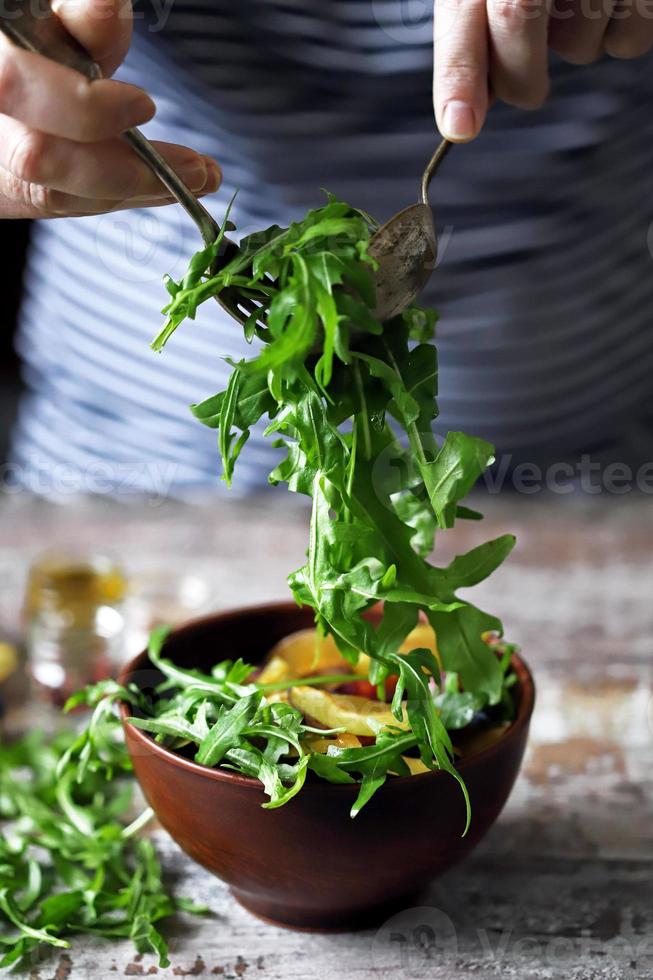 hälsosam salladsblandning manliga händer med en sked och gaffel. arugula plommonsallad. foto