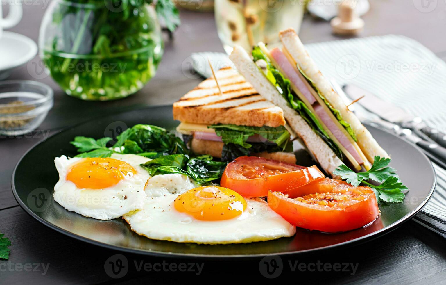 frukost. friterad ägg, spenat, tomater och klubb smörgås på tallrik. foto