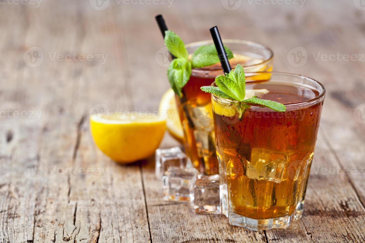 traditionellt iste med citron, mynta blad och isbitar i två glas på rustik träbord bakgrund. foto