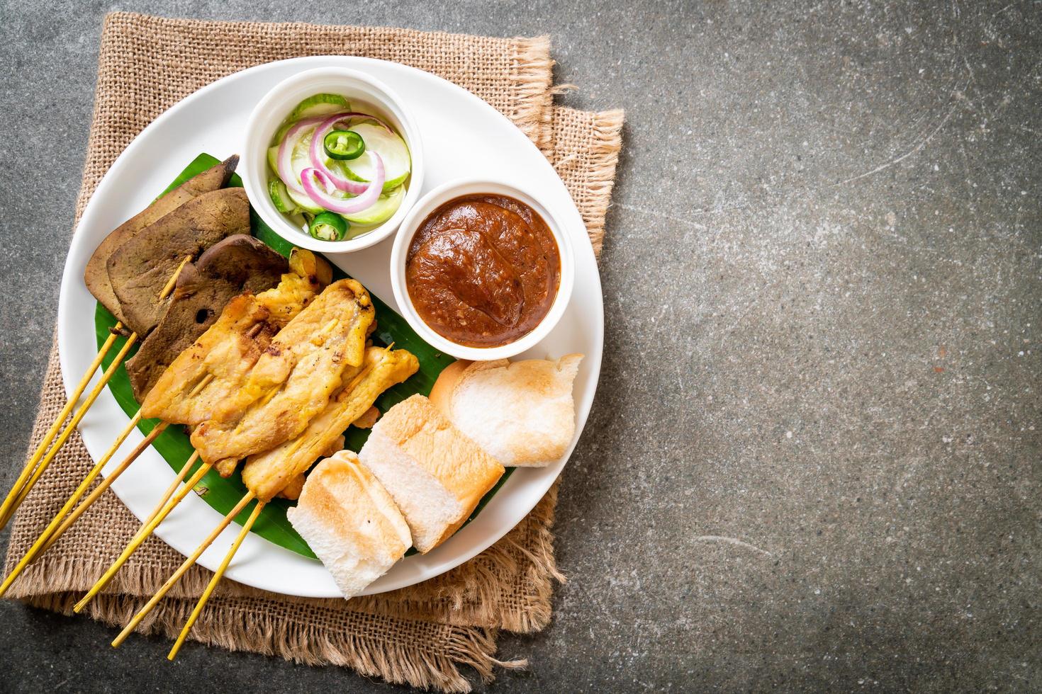 fläsk satay med din jordnötssås och pickles som är gurkskivor och lök i vinäger foto