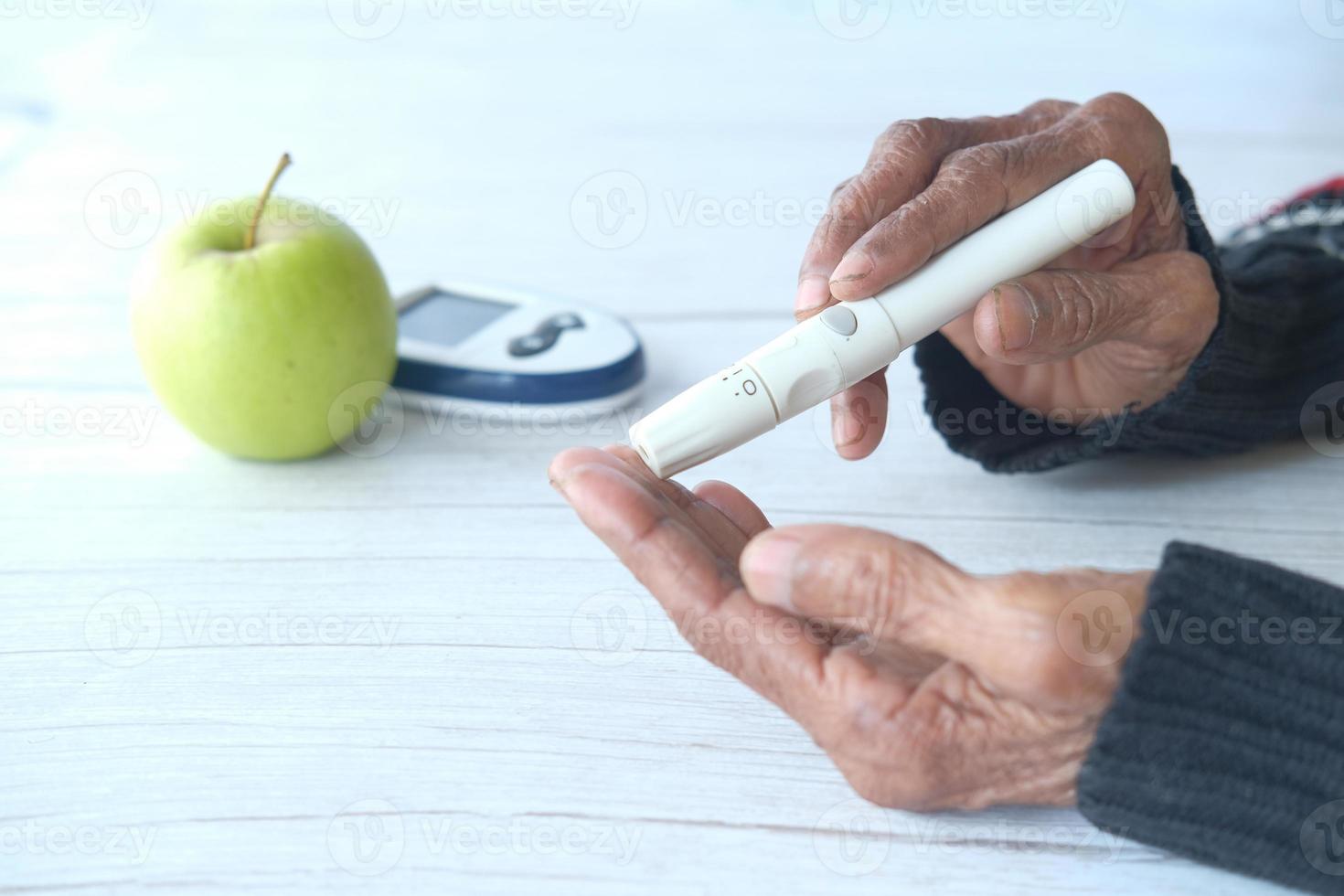äldre kvinnor diabetiker mäter glukosnivån hemma foto