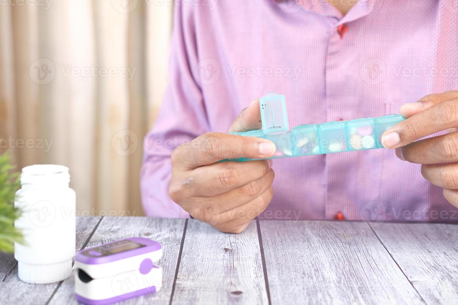 ung man händer tar medicin från en piller låda foto