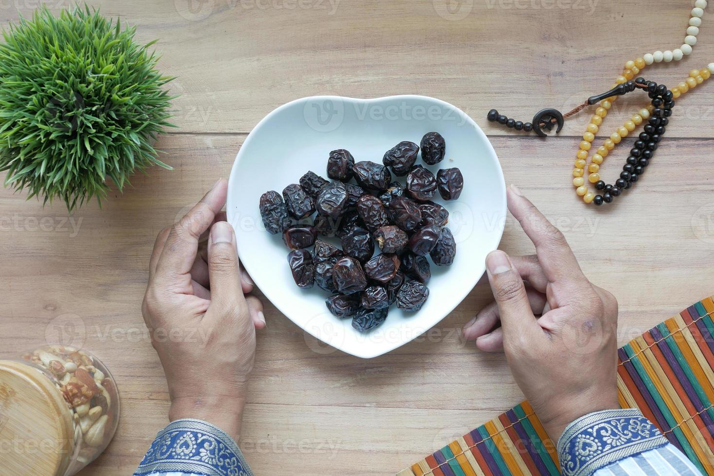 begreppet ramadan, hand som håller en skål med dadelfrukter foto