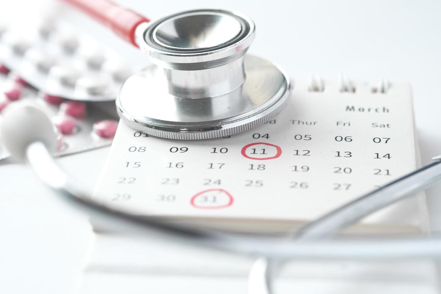 medicinska piller och stetoskop på kalendern på vit bakgrund foto