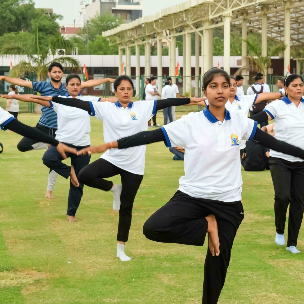 ny delhi, Indien, juni 21, 2023 - grupp yoga övning session för människor på yamuna sporter komplex i delhi på internationell yoga dag, stor grupp av vuxna delta yoga klass i cricket stadion foto