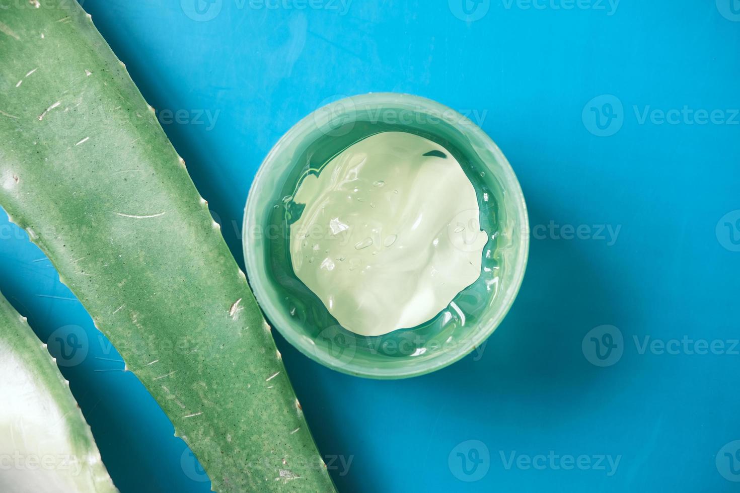 färsk aloe vera skivad och flytande gel i plastbehållare på grön bakgrund foto