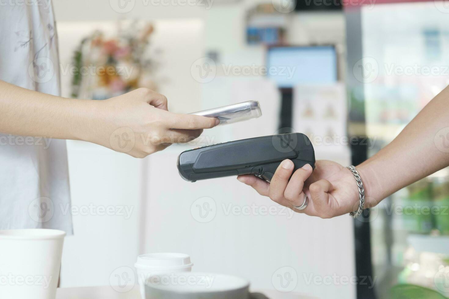 kvinna kund innehav telefon nära nfc terminal göra kontaktlös mobil betalning. foto