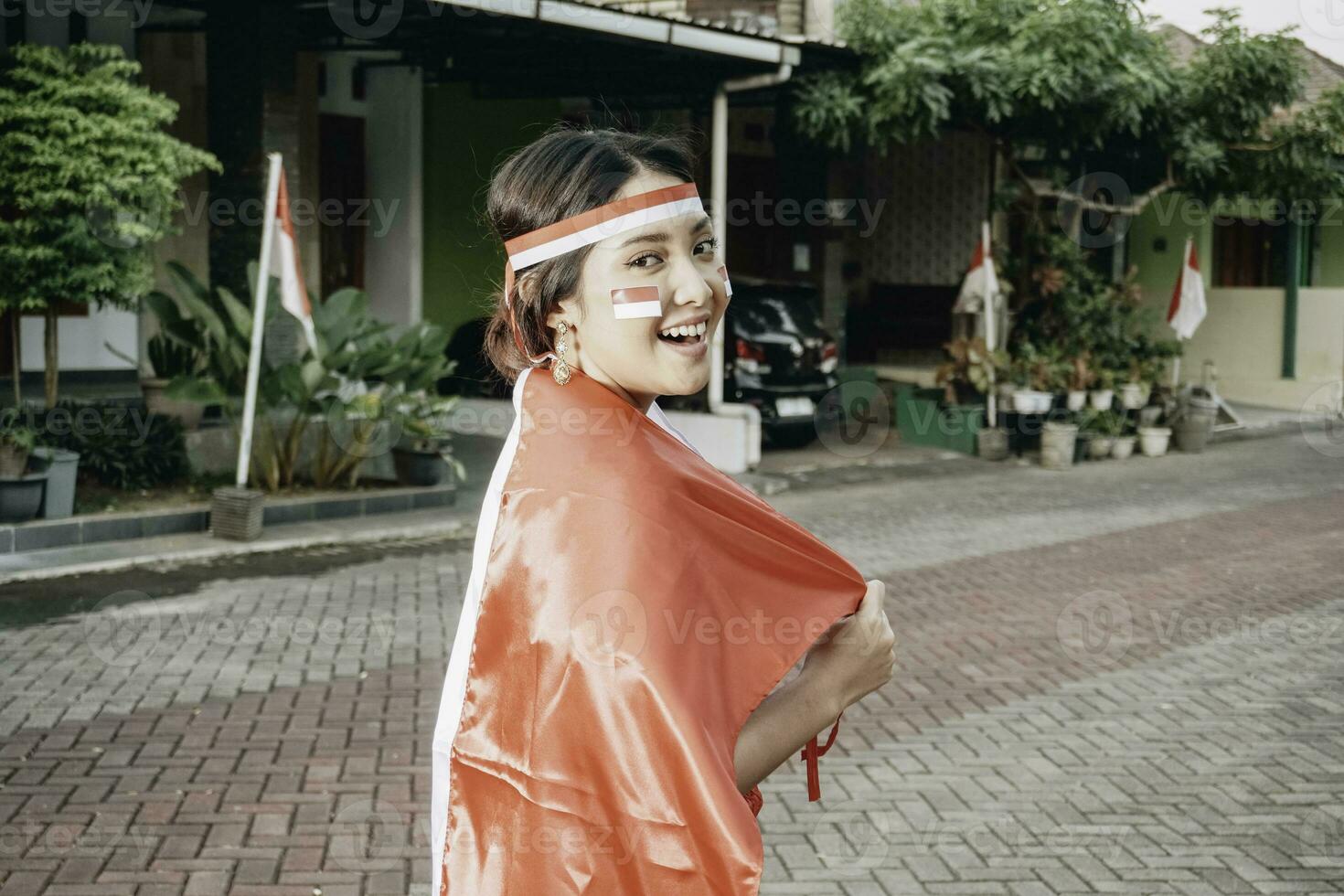 Lycklig leende indonesiska kvinna bär röd kebaya innehav Indonesiens flagga till fira indonesien oberoende dag. utomhus- fotografering begrepp foto