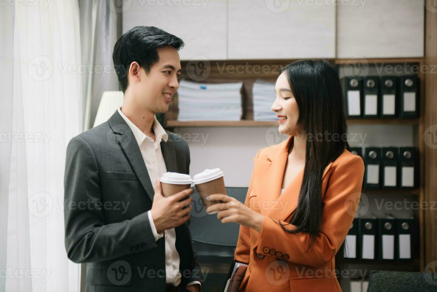 Lycklig två asiatisk företag kvinna innehav kaffe kopp i coworking kontor foto