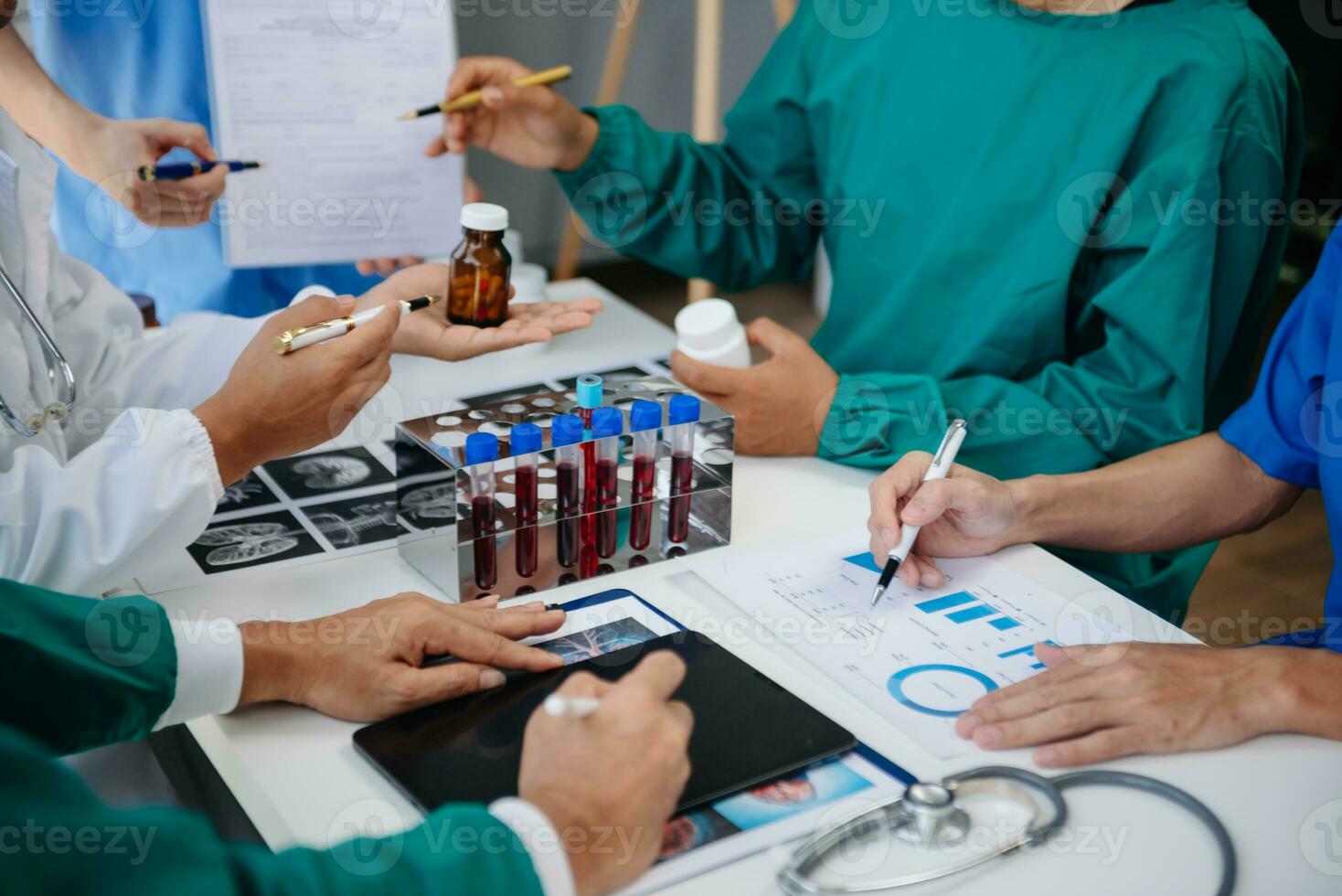 medicinsk team har en möte med doktorer i vit labb rockar och kirurgisk scrubs sittande på en tabell diskuterar en patienter arbetssätt uppkopplad använder sig av datorer i de medicinsk industri foto