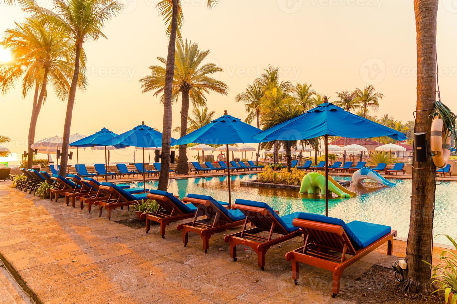 vackert paraply och stol runt poolen på hotell och resort foto