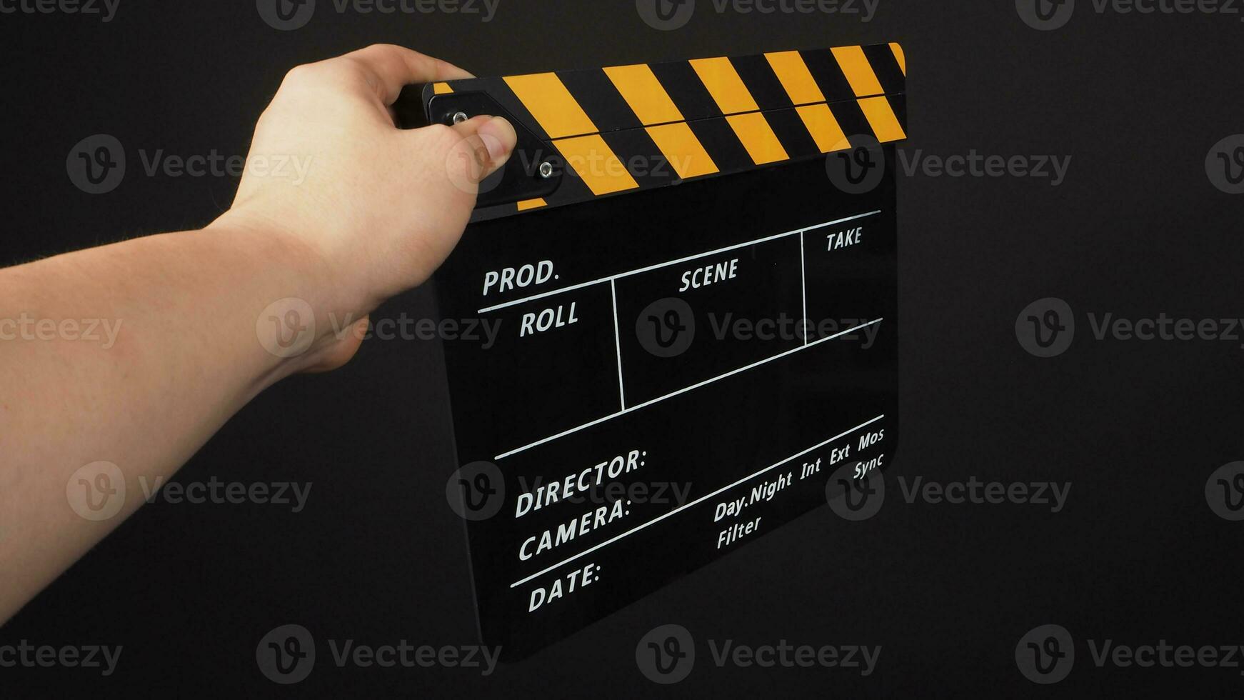 hand är innehav gul och svart Färg kläpp styrelse eller film skiffer på svart bakgrund. foto