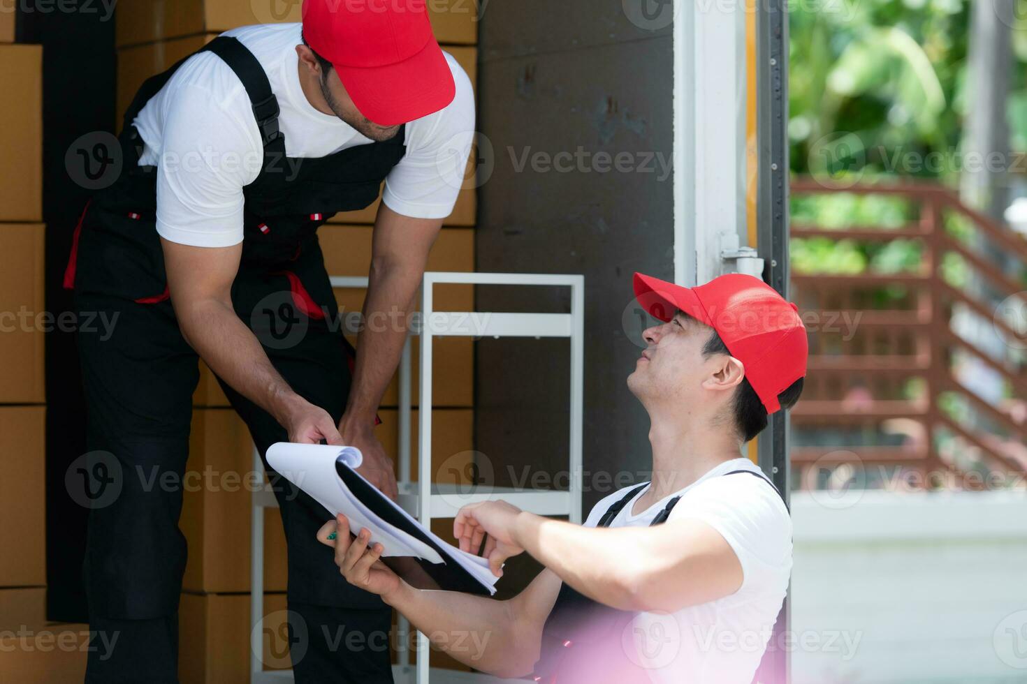 leverans man i röd keps och enhetlig leverera paket till mottagare - kurir service begrepp foto