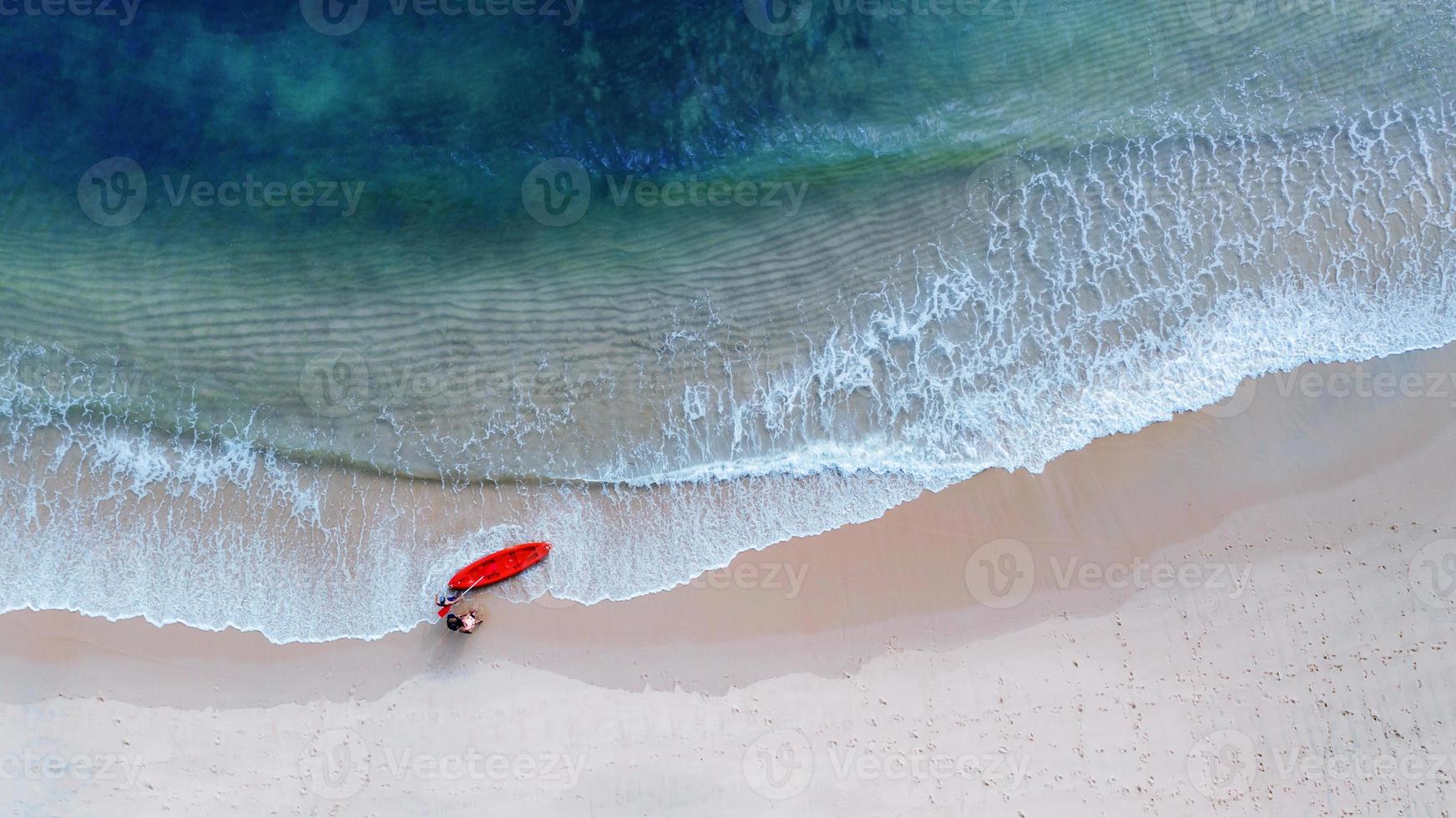 Flygfoto ovanifrån av kajakpaddling runt havet med skugga smaragdblått vatten och vågskum foto
