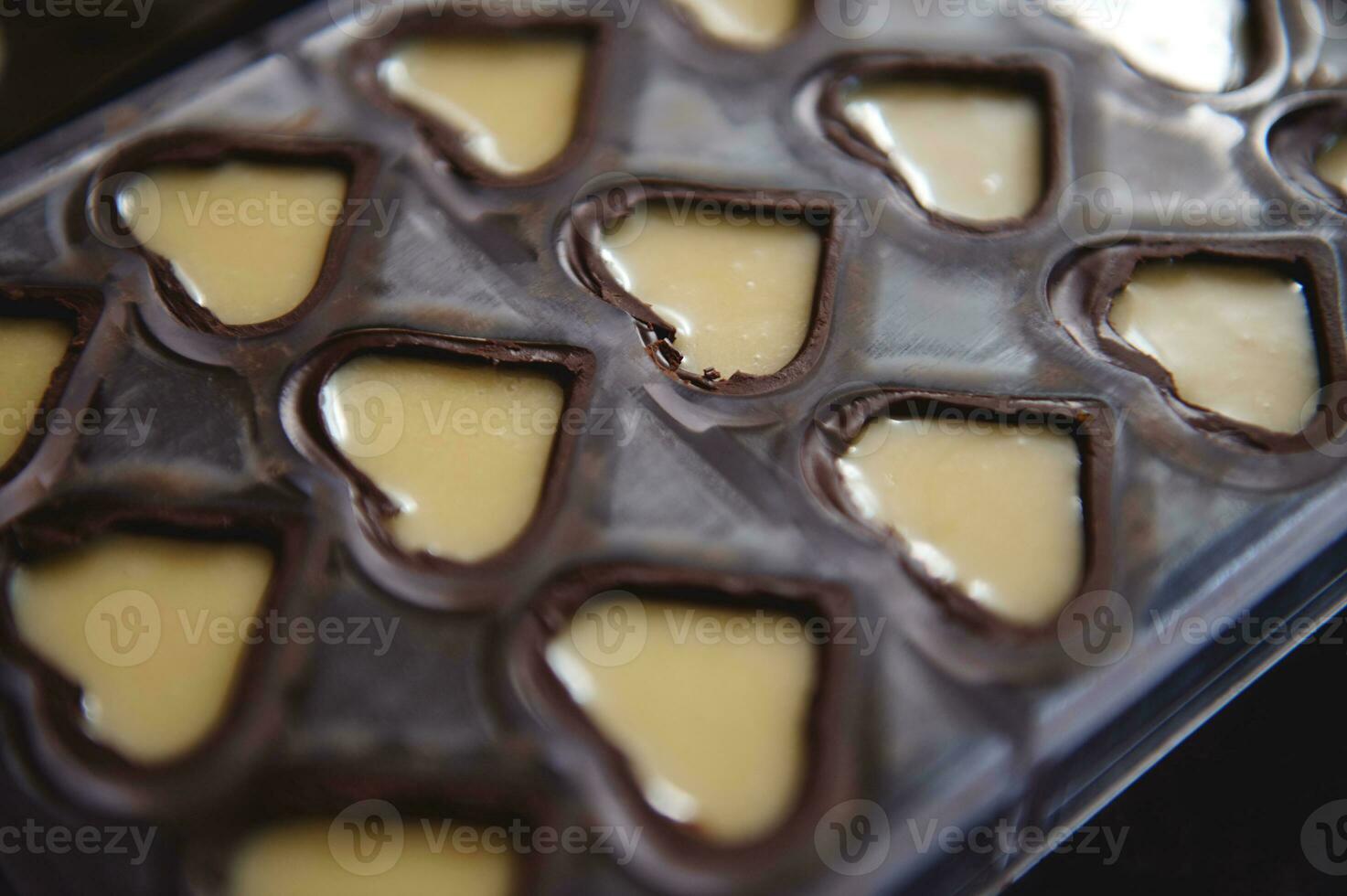 närbild av choklad formar i de form av hjärtan full av ljuv krämig fyllning foto