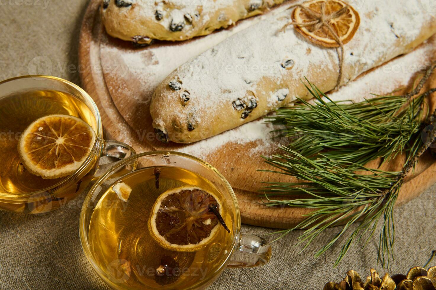 närbild av glas koppar med ört- te och skivor av torkades citrus- Nästa till en trä- styrelse med hemlagad utsökt nyligen bakad tysk traditionell stollen bröd stänkte med glasyr socker. jul. foto