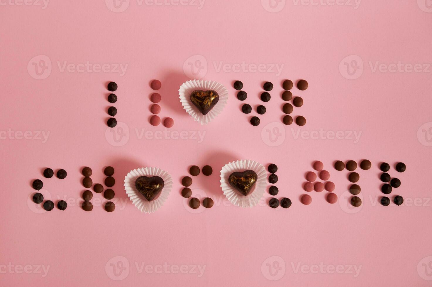 platt lägga av jag kärlek choklad text lagd ut från mång färgad choklad piller och praliner på rosa bakgrund med kopia Plats foto