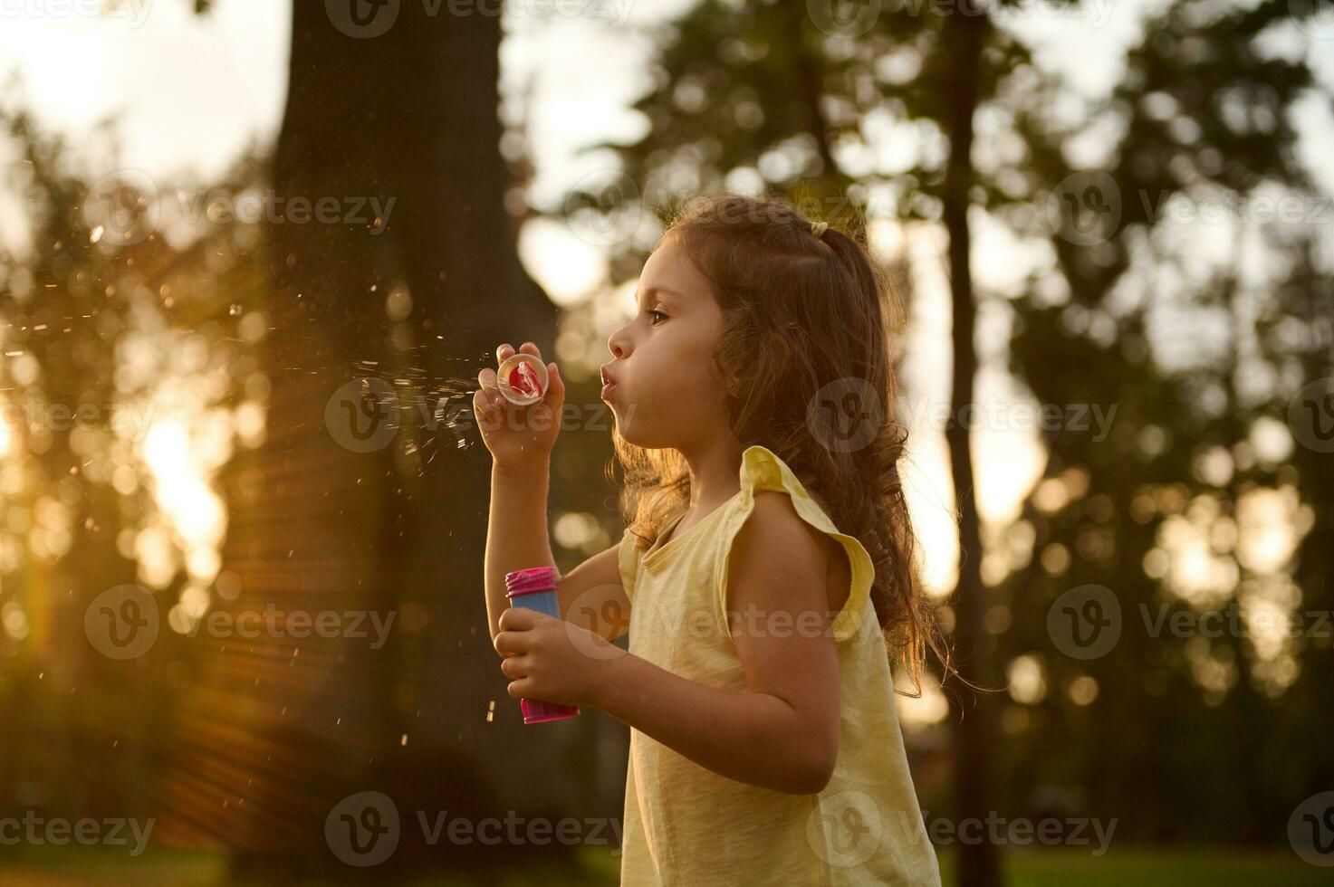 skön underbar söt förtjusande liten barn flicka blåser tvål bubblor på solnedgång. sorglös barndom, utomhus fritid aktiviteter. bebis flicka spelar spel i de natur foto