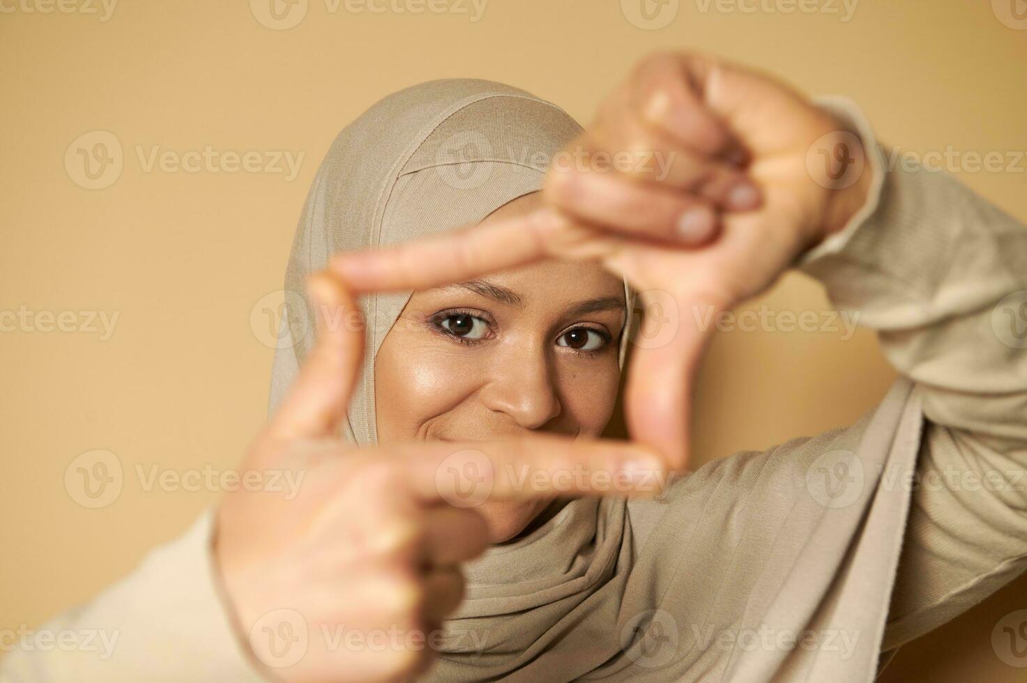 närbild av ett attraktiv se av skön arab muslim kvinna i hijab genom finger ramar foto