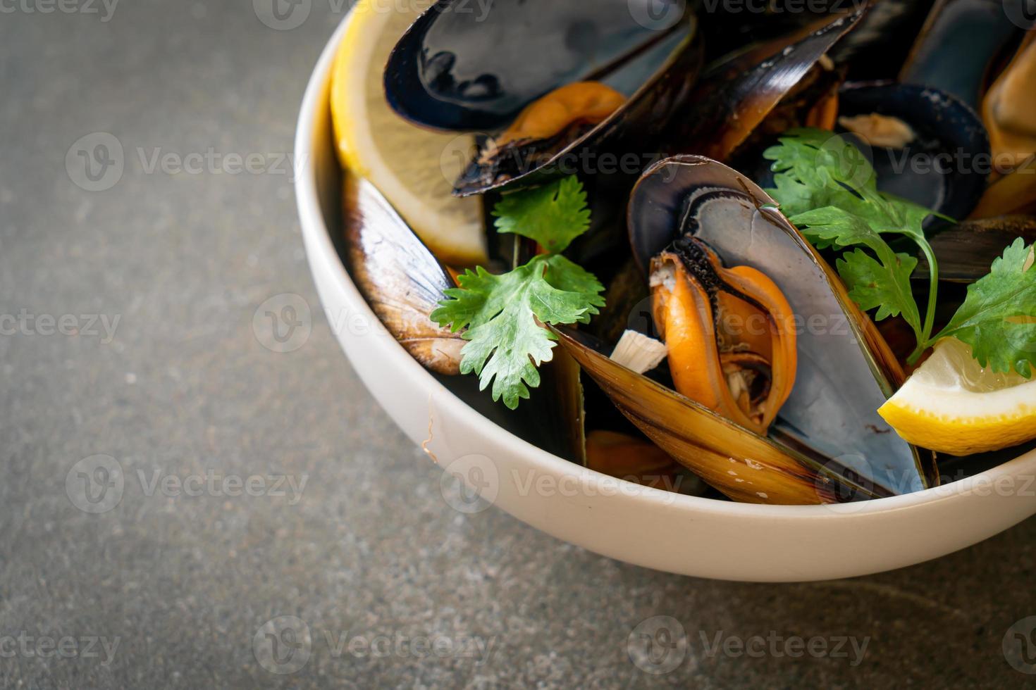 musslor med örter i en skål med citron foto