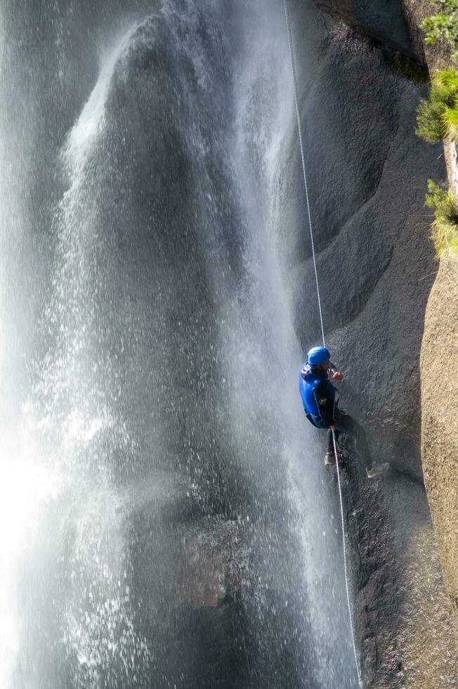 en person på en rep klättrande upp en vattenfall foto