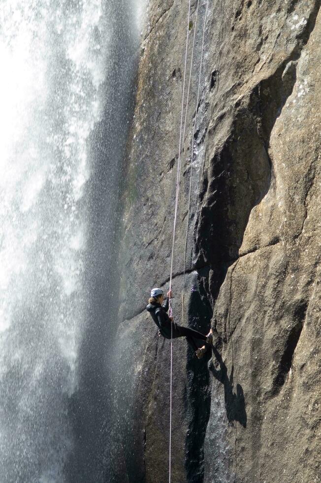 en person på en rep klättrande upp en vattenfall foto