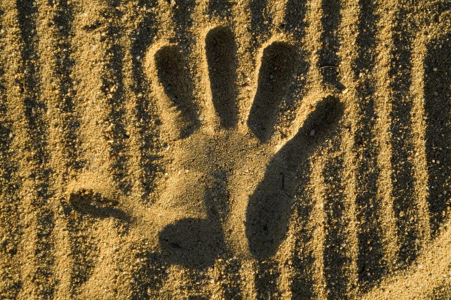 en hand skriva ut i de sand med två händer foto