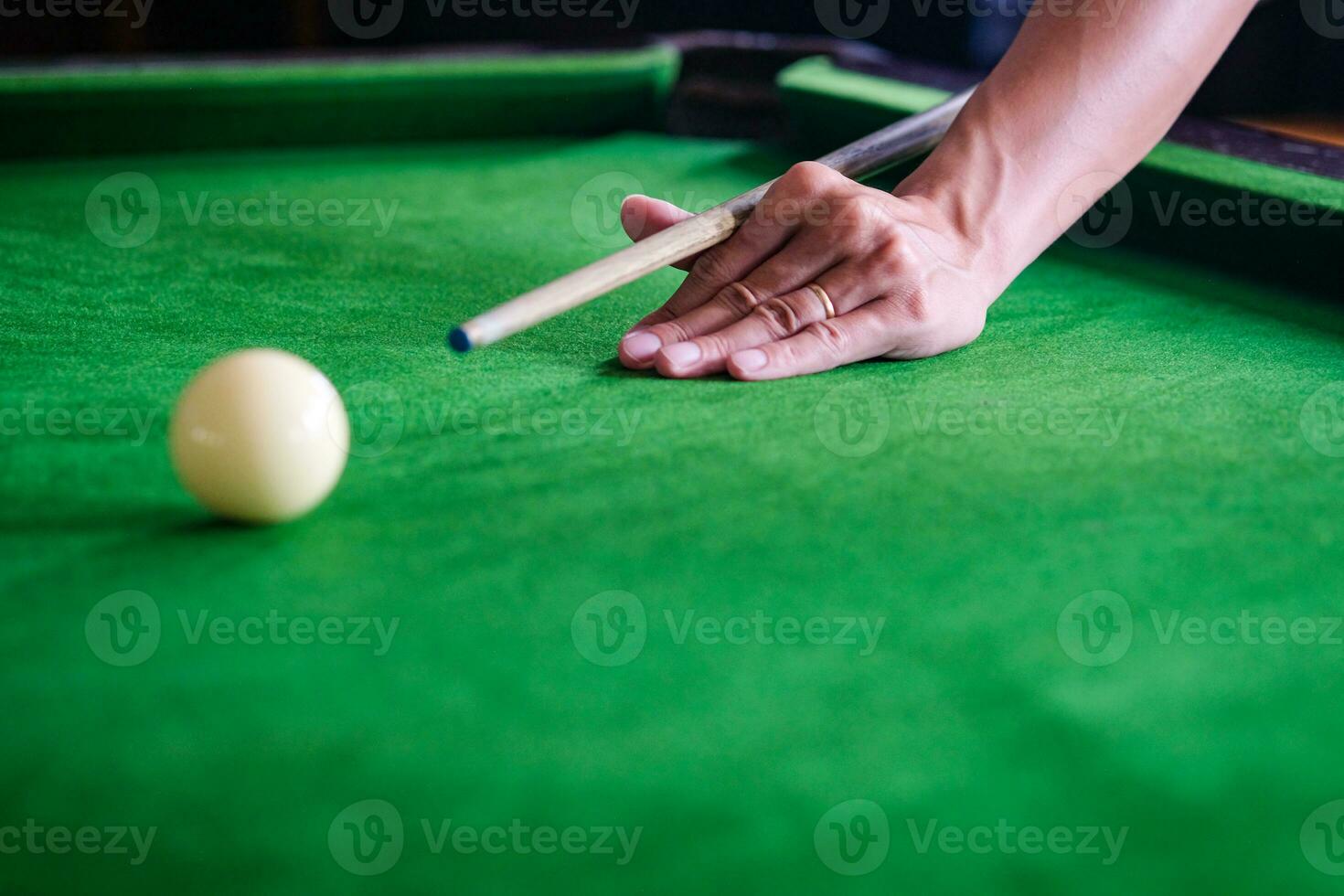 mannens hand och kö ärm spelar snooker spel eller framställning siktar till skjuta slå samman bollar på en grön biljard tabell. färgrik snooker bollar på grön fris. foto