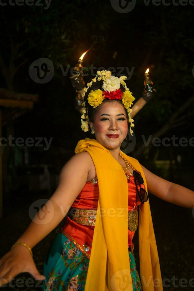 en traditionell javanese dansare danser med färgrik blommor på henne näve medan på skede foto