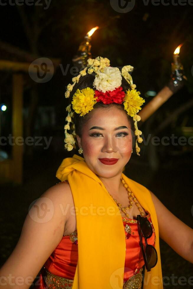 en traditionell javanese dansare danser med färgrik blommor på henne näve medan på skede foto