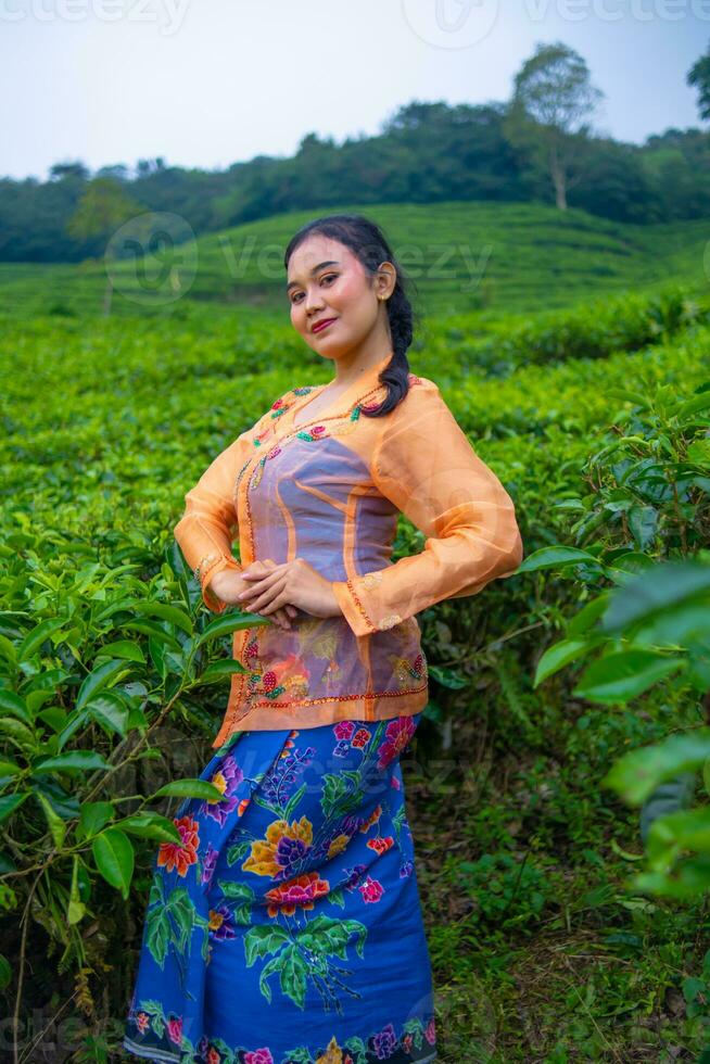 en te blad jordbrukare i ett orange klänning Framställ i främre av en mycket skön te trädgård foto