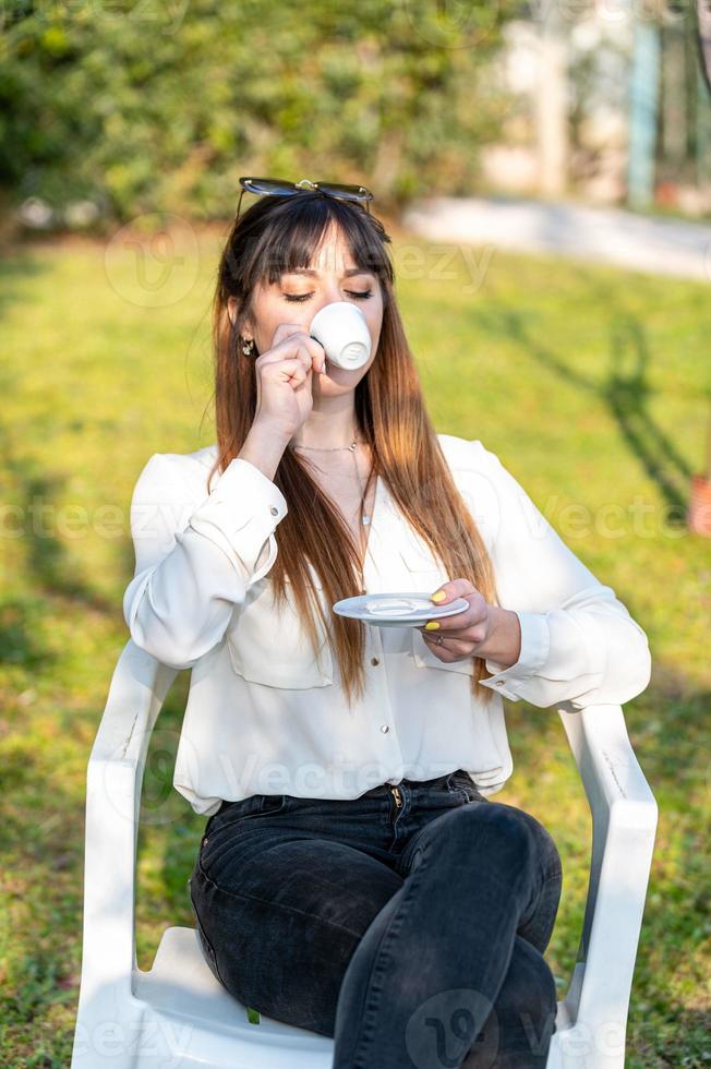 flicka som dricker kaffe i trädgården foto