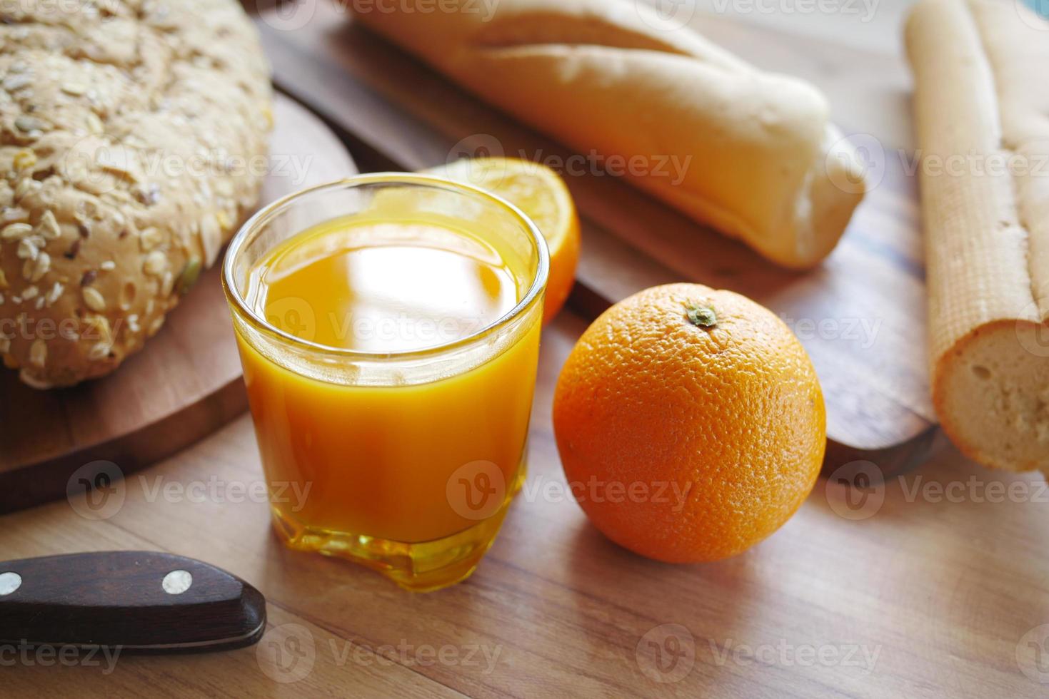 glas apelsinjuice och fullkornsbröd på bordet foto