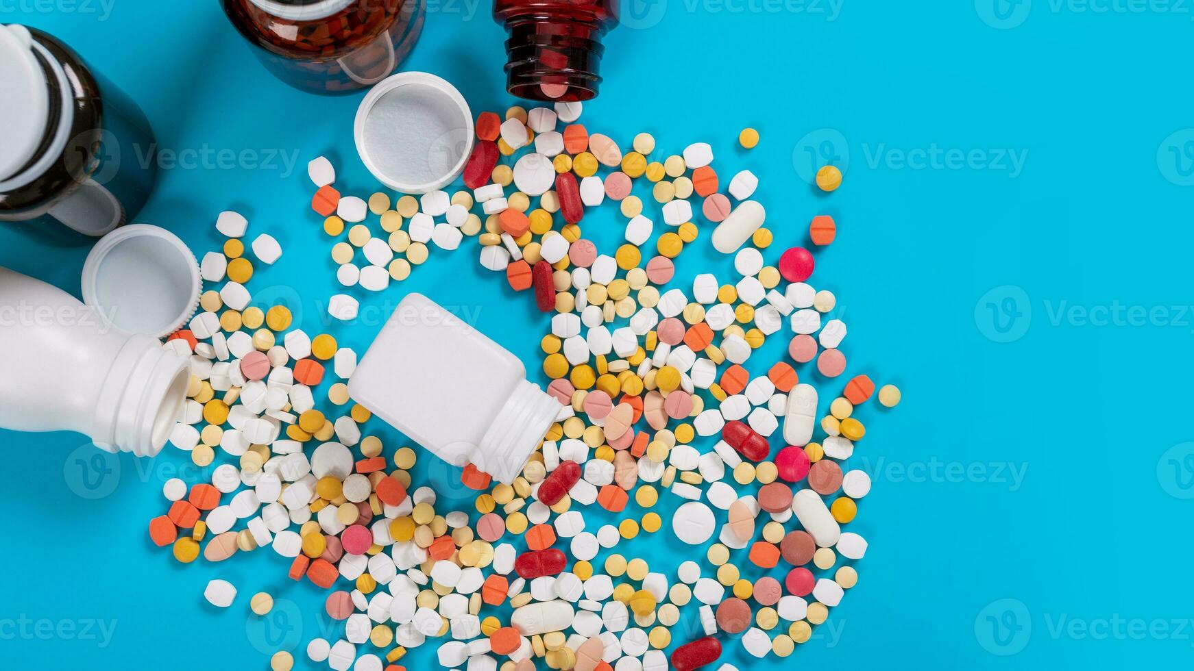 medicinsk piller och tabletter spill ut av en läkemedel flaska på blå bakgrund foto