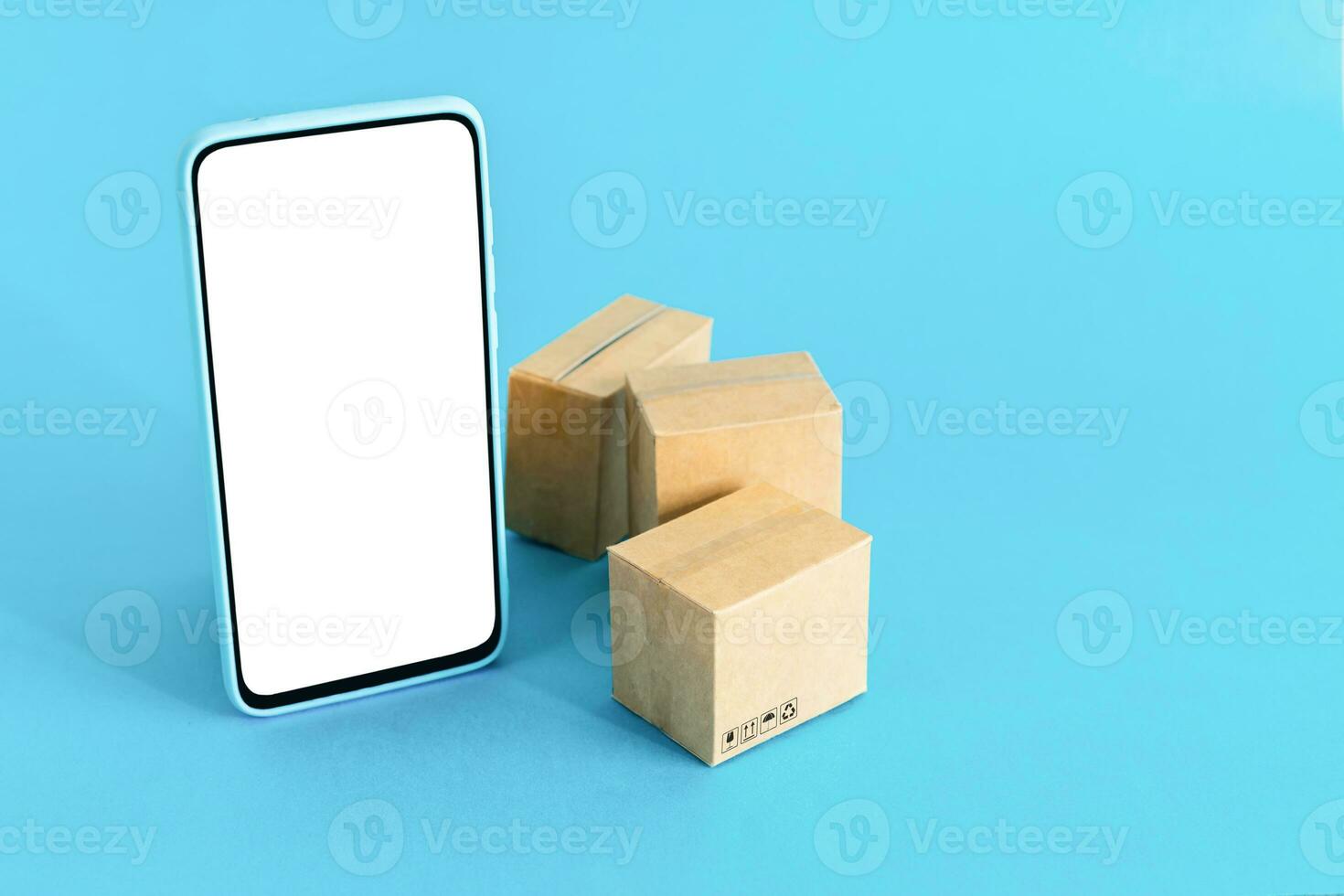smart telefon med tom skärm och kartong lådor på ljus blå bakgrund. uppkopplad handla och leverans service begrepp. foto