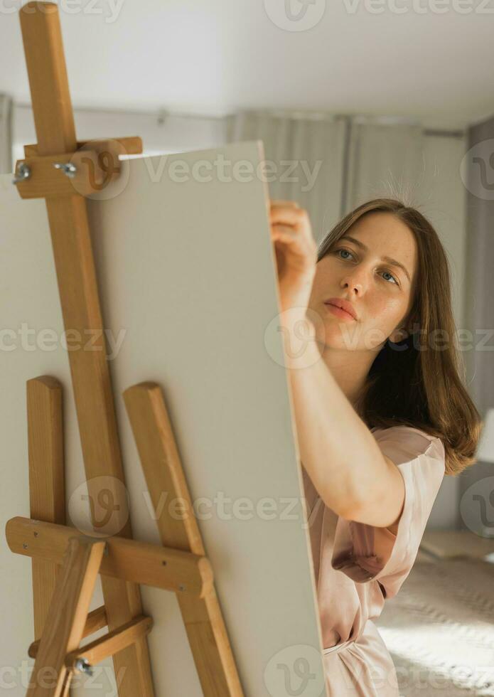 ung närbild kvinna konstnär målning på duk på de staffli på Hem i sovrum - konst och kreativitet begrepp foto