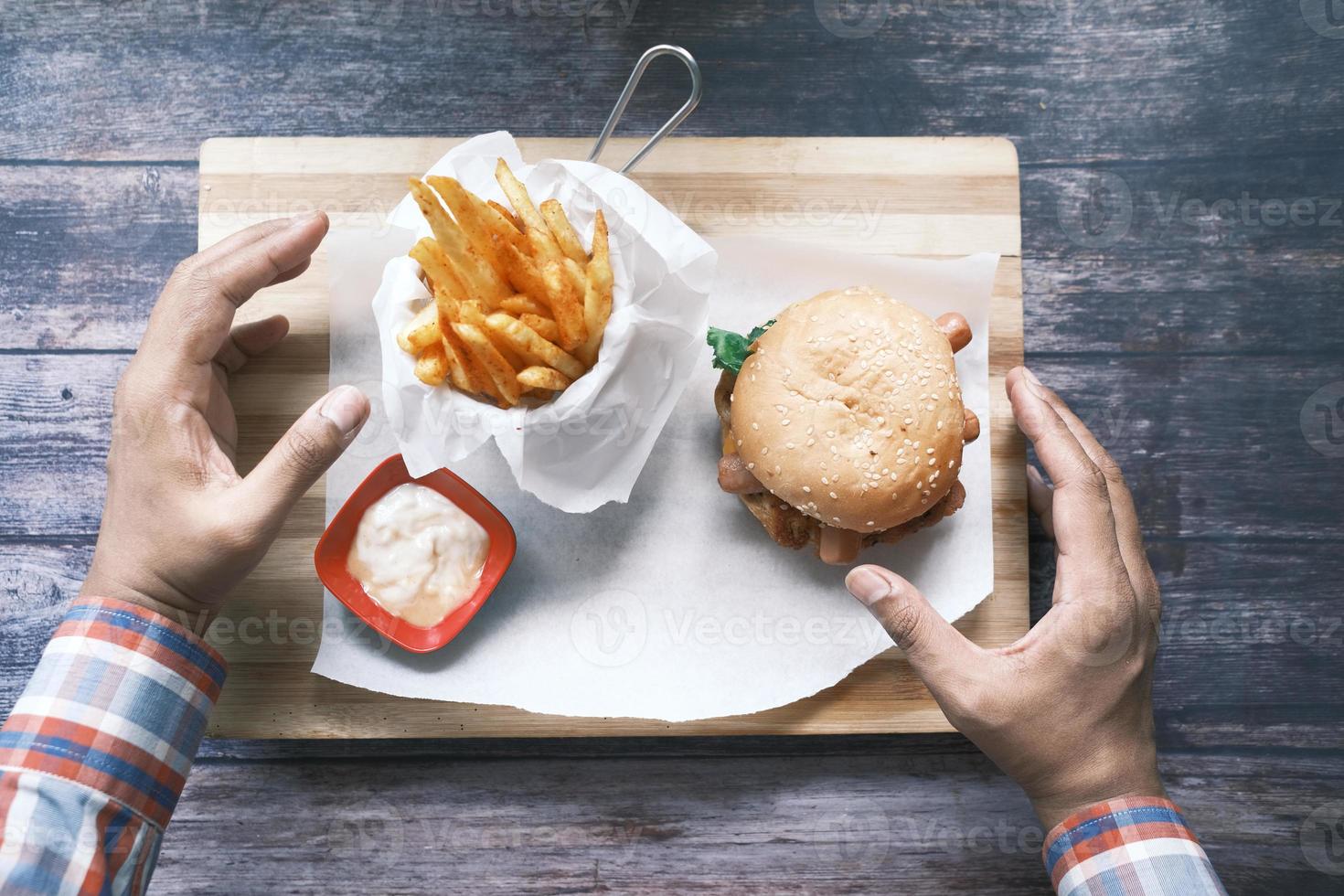 hand som håller nötköttburger på bordet, ovanifrån foto