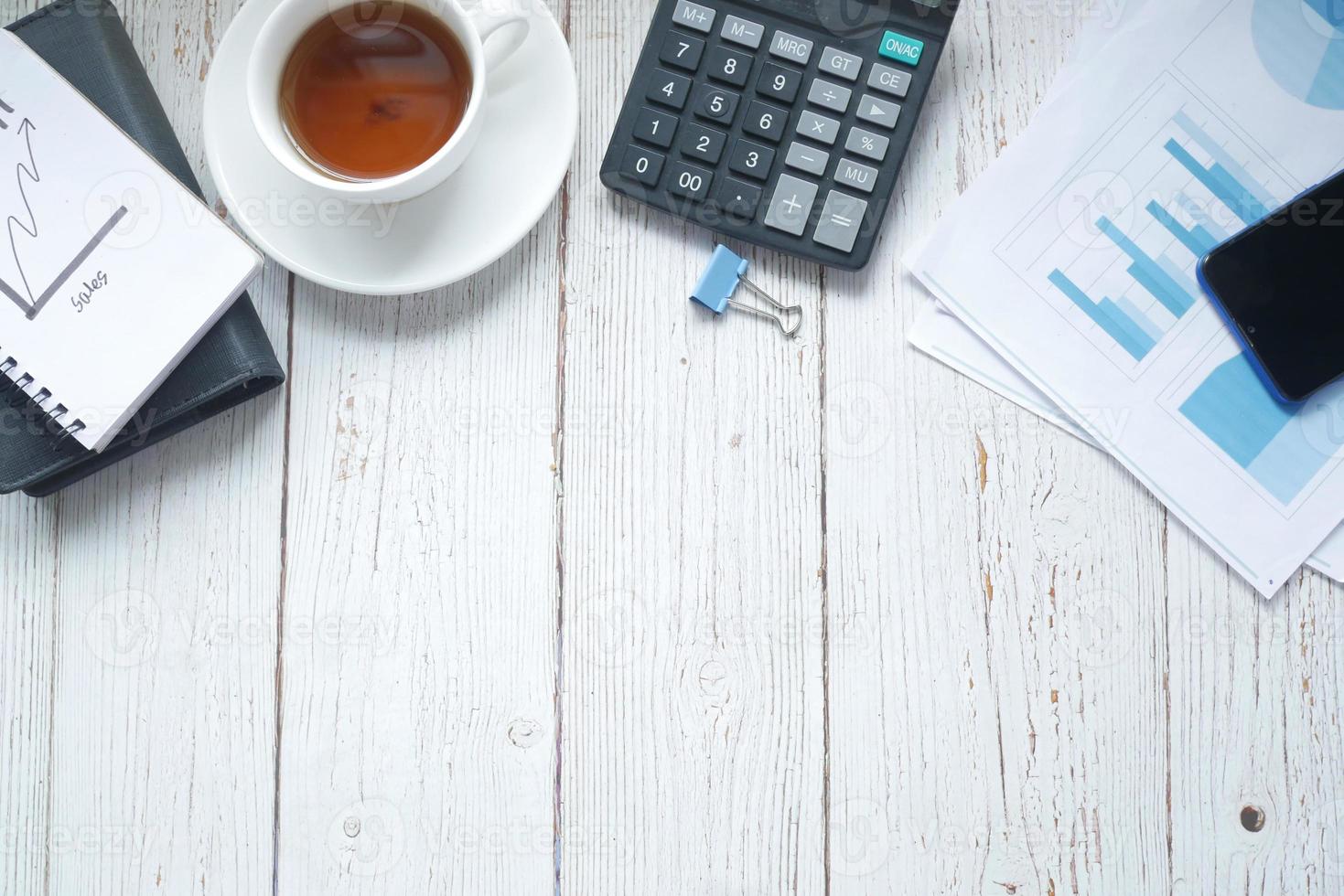 kontorsskrivbord med finansiell graf, miniräknare och anteckningsblock på bordet foto