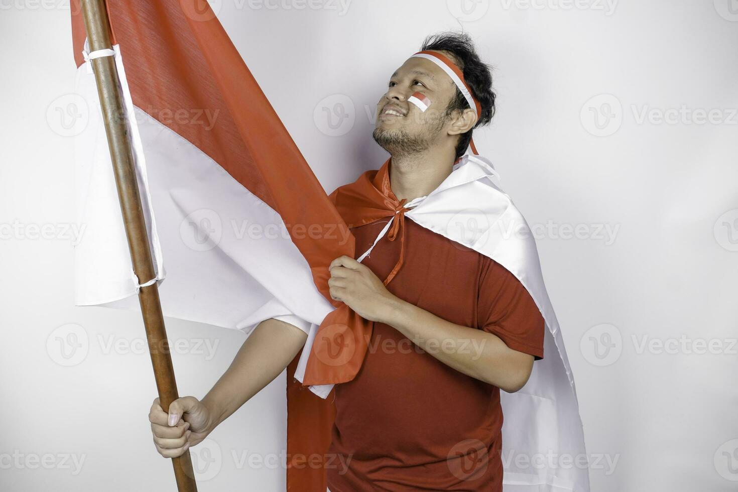 Lycklig leende indonesiska man innehav Indonesiens flagga till fira indonesien oberoende dag isolerat över vit bakgrund. foto