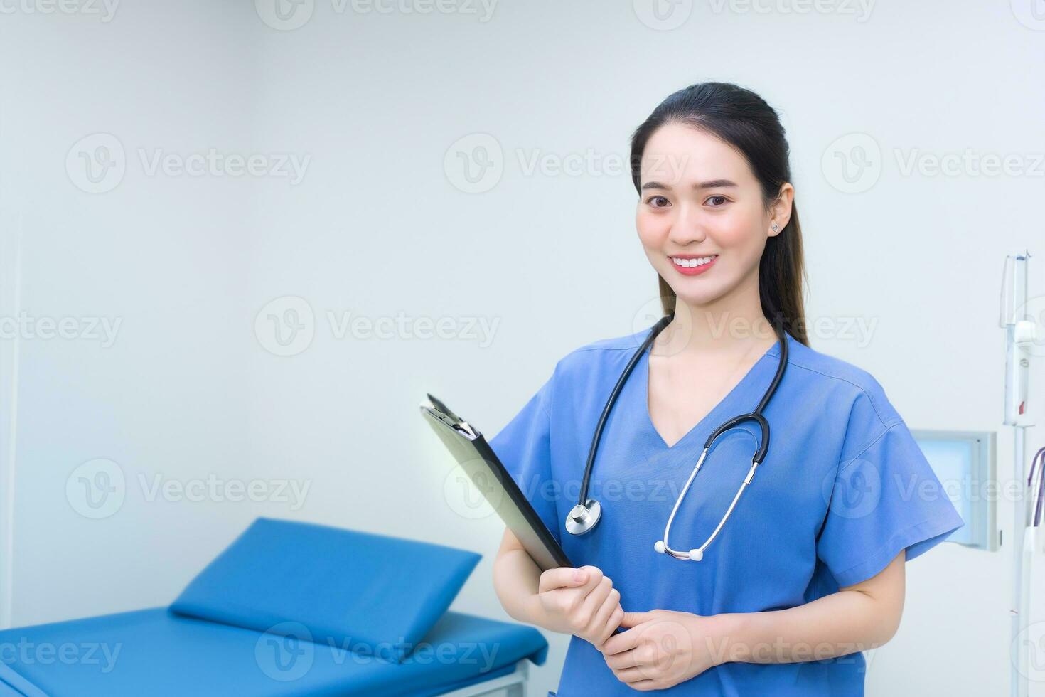 professionell ung asiatisk kvinna läkare stående leende i medicinsk enhetlig blå labb skjorta innehav patient dokument i hand undersökning rum i de sjukhus. hälsa vård koncept. foto