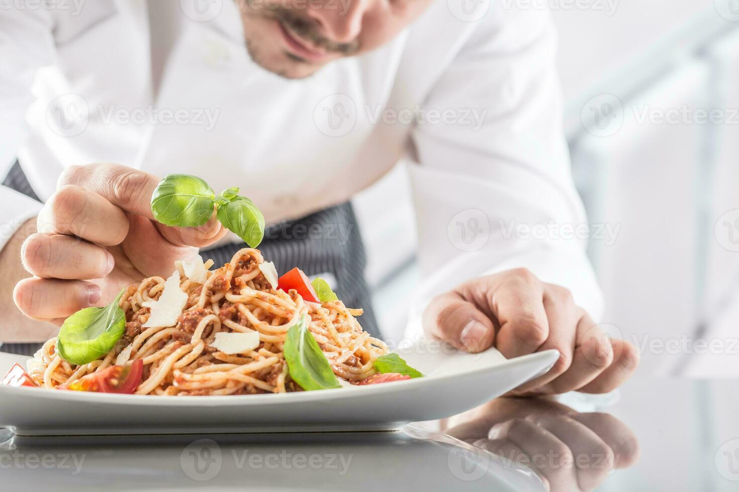 kock i restaurang kök förbereder och dekorerar måltid med händer.koka framställning spaghetti bolognese foto