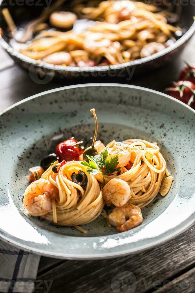 pasta spaghetti på tallrik och panorera med räka tomat sås toater och örter. italiensk eller medelhavs kök foto