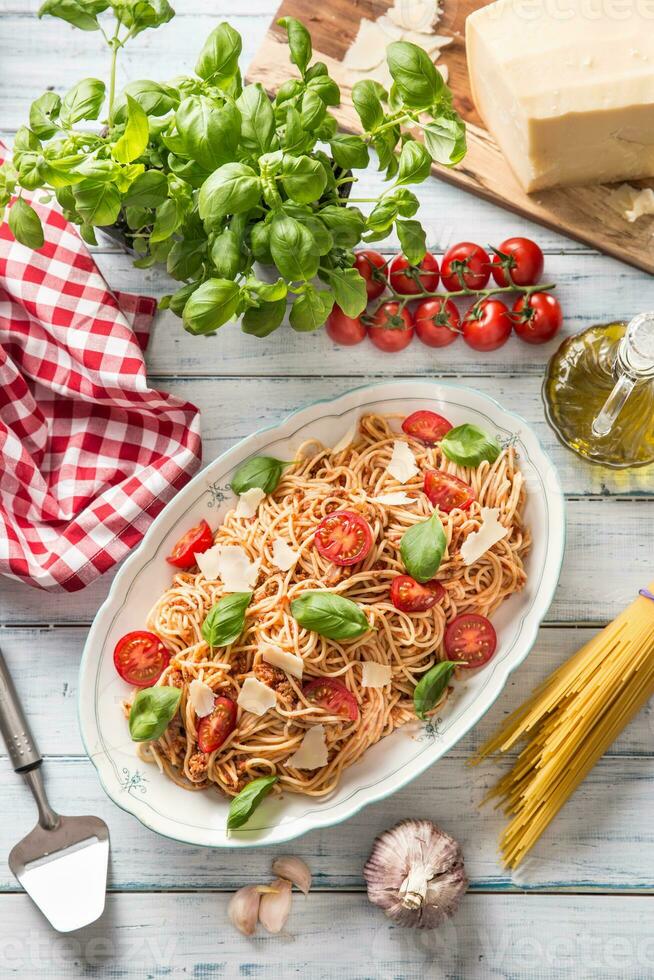 italiensk pasta spaghetti bolognese i vit skål med tomater parmesan ost och basilika foto