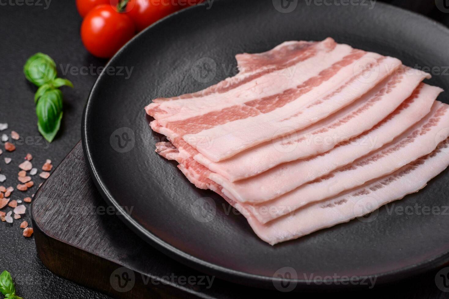 färsk rå bacon skära in i skivor med salt, kryddor och örter foto