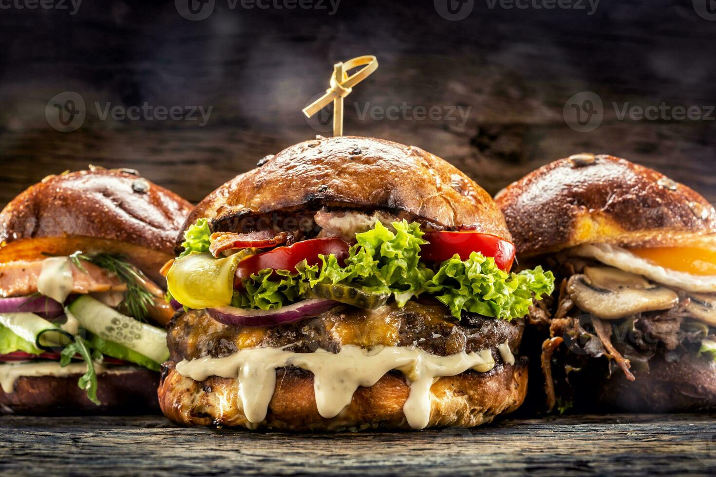 främre se på tre stor, nötkött lax och kebab hamburgare fylld med färsk vegetabiliska sallad och klä på sig foto