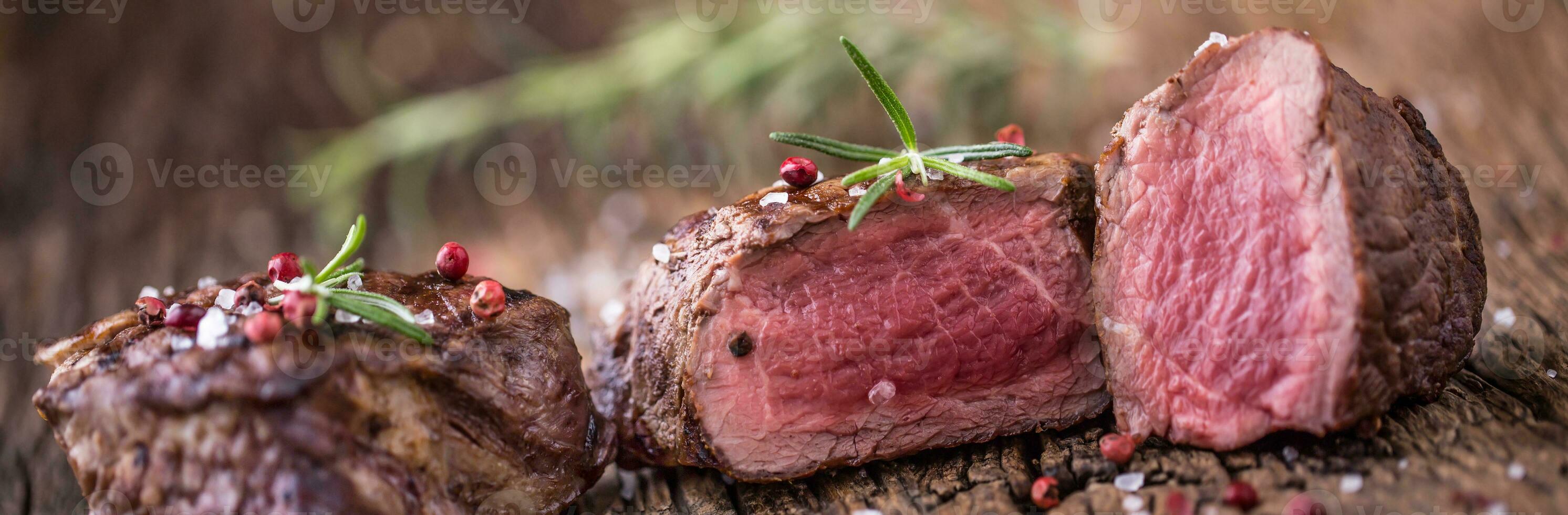 grillad nötkött biff med rosmarin, salt och peppar på gammal skärande styrelse. nötkött fläskkarré biff. foto