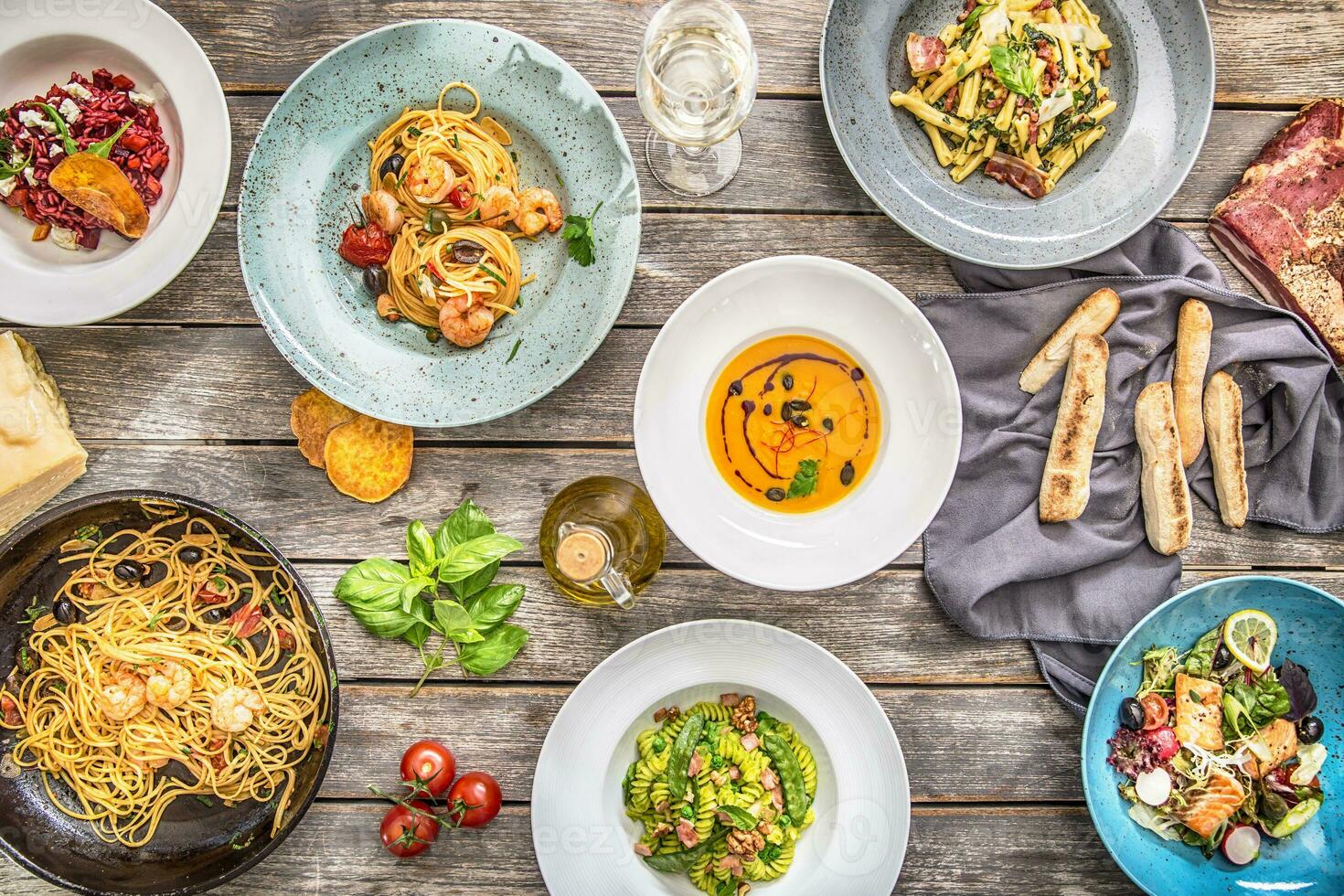 topp av se italiensk måltider på plattor ett d panorera. pasta risotto soppa och fisk vegetabiliska sallad foto